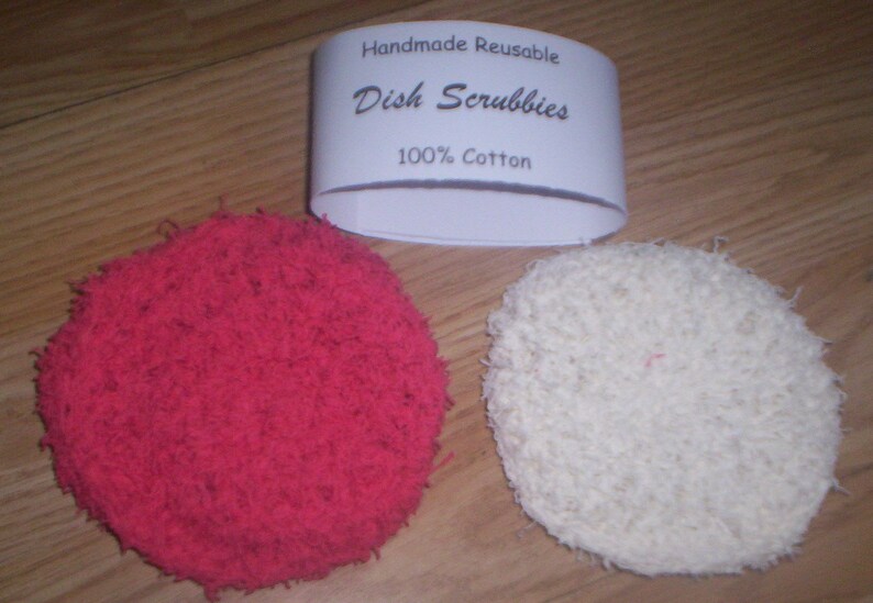 May include: Two handmade, reusable dish scrubbies made of 100% cotton. One is red and the other is white.