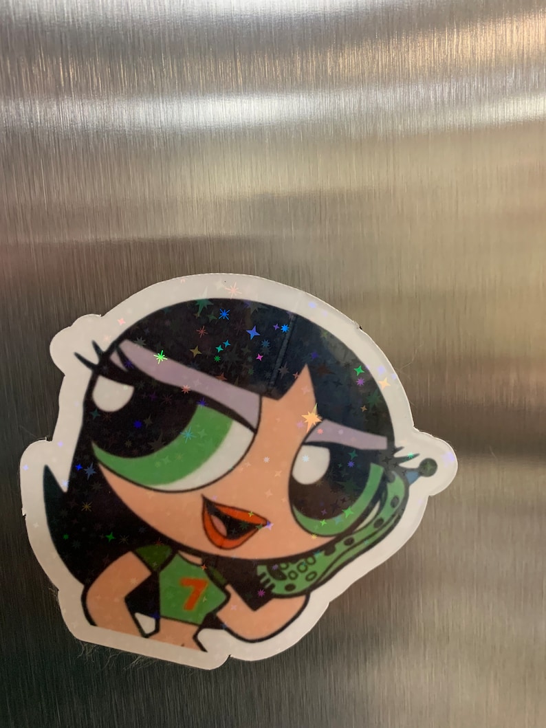May include: A green, black, and white cartoon sticker of a girl with green eyes and black hair. She is wearing a green shirt with a number 7 on it. She is holding a green phone to her ear. The sticker has a glittery finish.
