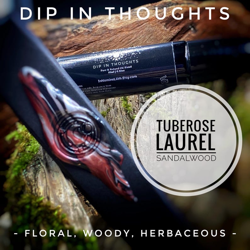 May include: A black essential oil bottle with the text "DIP IN THOUGHTS" and "TUBEROSE LAUREL SANDALWOOD". The bottle has a decorative design with red and white accents. The text "- FLORAL, WOODY, HERBACEOUS -" is also visible.
