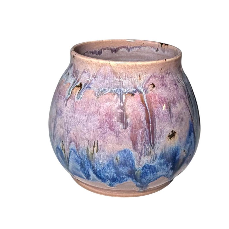 May include: A handcrafted ceramic vase with a rounded shape. The vase features a blend of colors, including pink, purple, and blue, with a glossy finish. The glaze has a dripped effect, adding to its unique appearance. This decorative vase is suitable for home decor.