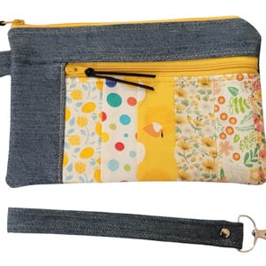 May include: A denim and yellow fabric zippered pouch with a floral print and a detachable denim strap with a silver clasp.