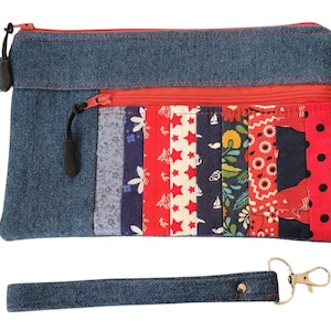 May include: A denim clutch purse with a red zipper and a colorful patchwork fabric lining. The purse has a detachable denim strap with a silver key ring.