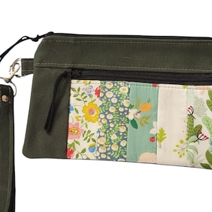 May include: A green canvas zippered pouch with a floral patterned fabric lining. The pouch has a detachable strap.