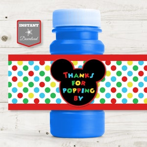 May include: A blue plastic bottle with a label that says "Thanks for popping by" with a Mickey Mouse head silhouette and a polka dot background. The label is red, white, green, yellow, and black.