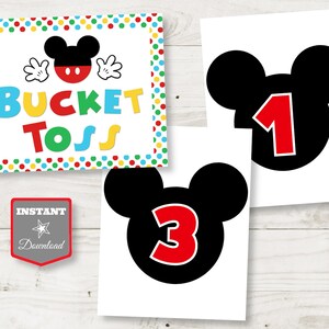 May include: Printable party decorations with a Mickey Mouse theme. Includes a "Bucket Toss" sign with colourful polka dots and a Mickey Mouse silhouette, and two cards with the numbers 1 and 3 inside a Mickey Mouse head.