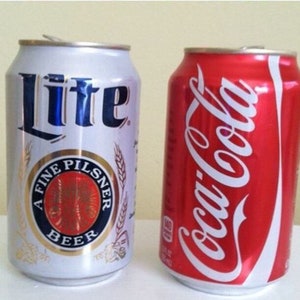 May include: Two aluminum beverage cans, one silver with the word "Lite" and a red circle with the words "A Fine Pilsner Beer", and the other red with the white text "Coca-Cola"