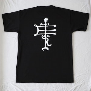 May include: Black t-shirt with a white graphic of a symbol with the words "Omega" and "Agla" on it.