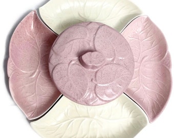 Può includere: Un piatto da portata in ceramica rosa e bianco con coperchio. Il piatto è diviso in quattro sezioni e presenta un motivo a foglie.