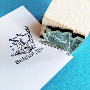 Könnte beinhalten: Eine Schwarzweißillustration eines Hundes, der auf einem Buch steht, mit Papier, das um ihn herumfliegt. Der Text "HAUSAUFGABE FEHLT!" ist unter dem Bild gedruckt.