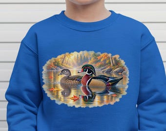 May include: A bright blue long-sleeve sweatshirt featuring a central oval graphic print of two wood ducks swimming on a calm pond surrounded by autumn foliage. The design includes detailed illustrations of the ducks with vibrant plumage colors.