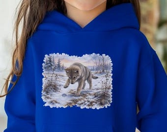 May include: A bright royal blue hooded sweatshirt featuring a rectangular graphic print on the chest. The print depicts a grey wolf walking through a snowy, frost-covered landscape with bare trees and winter vegetation under a pale sky.
