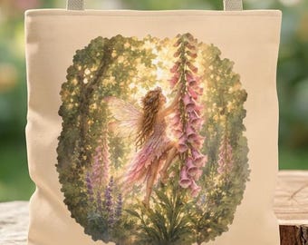 May include: A beige tote bag featuring a circular illustration of a fairy with translucent wings standing among tall pink foxglove flowers in a lush, sunlit forest setting. The bag has two matching beige fabric handles attached at the top.