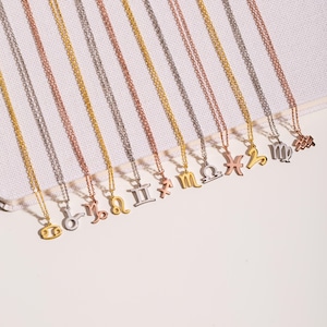 May include: A set of 12 gold, silver, and rose gold necklaces with zodiac signs as pendants. The signs are: Cancer, Leo, Virgo, Libra, Scorpio, Sagittarius, Capricorn, Aquarius, Pisces, Aries, Taurus, and Gemini.