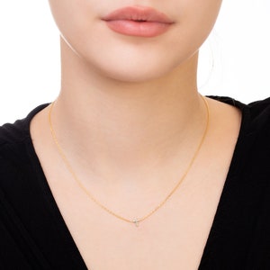Pu&ograve; includere: Una delicata collana d'oro con un piccolo pendente a forma di croce. La collana &egrave; indossata su un top nero, creando un contrasto che mette in risalto il gioiello. Il pendente a forma di croce sembra avere piccoli dettagli scintillanti.