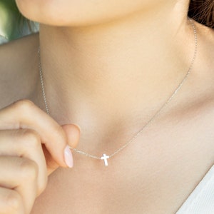 May include: A silver chain necklace with a small silver cross pendant.