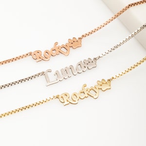 May include: Three gold, silver, and rose gold necklaces with paw print charms and personalized nameplates. The nameplates read "Rocky" and "Lumas".