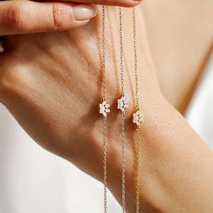 May include: Three delicate gold chains with paw print charms. Each charm has a different name engraved on it: "Charlie", "Luna", and "Yoda".