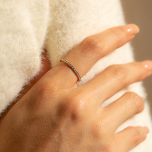 May include: A delicate gold band ring with a row of small blue gemstones.