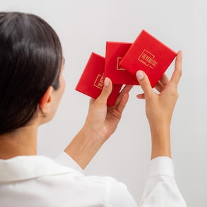 May include: Three red boxes with the text "SILVERISTIC" in gold lettering. The boxes are being held by a person.