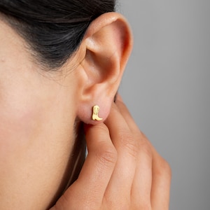 Può includere: Orecchini a bottone dorati con un piccolo design di stivale da cowboy dettagliato.