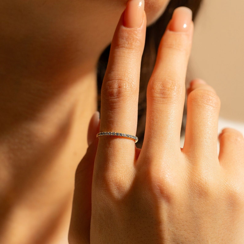 May include: A delicate gold band ring with a row of small blue gemstones.