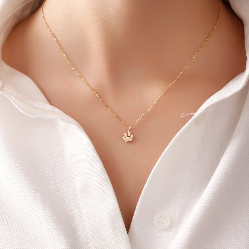 May include: A gold chain necklace with a small paw print pendant.