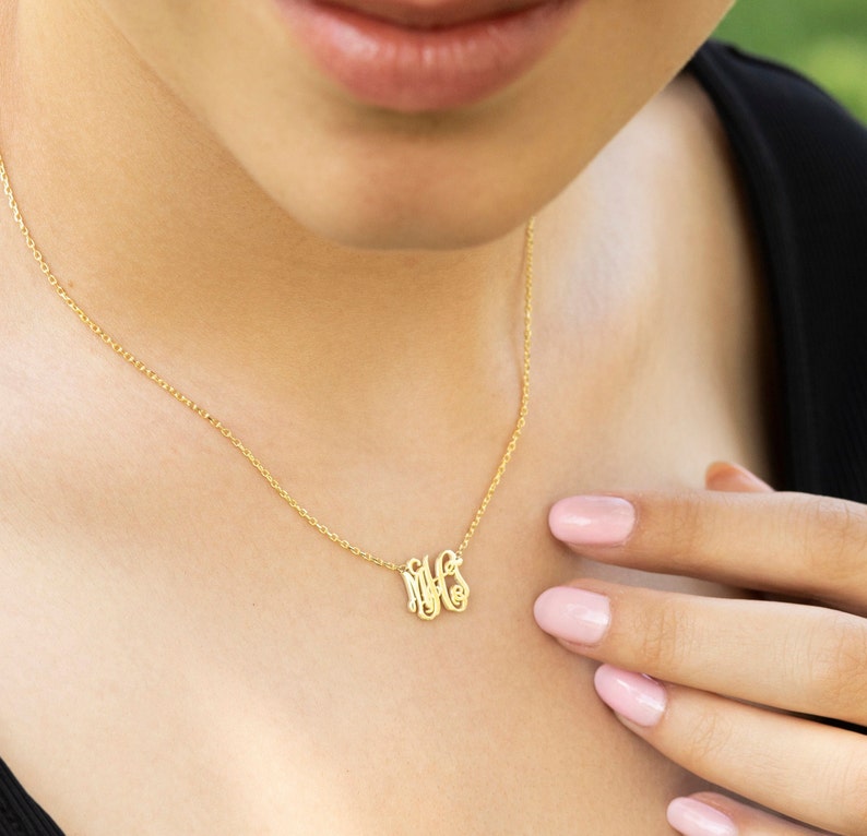 May include: A gold chain necklace with a delicate monogram pendant featuring the letters "MFS".
