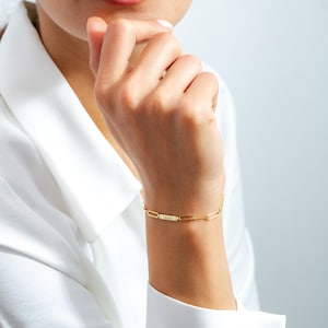 May include: A gold chain bracelet with a personalized nameplate that reads "SARAH".