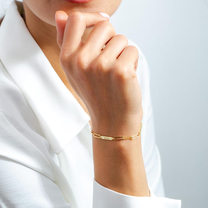 May include: A gold chain bracelet with a personalized nameplate that reads "SARAH".