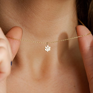 Op de afbeelding: Een gouden ketting met een kleine gouden pootprint bedel. De bedel heeft de naam "Jack" gegraveerd.