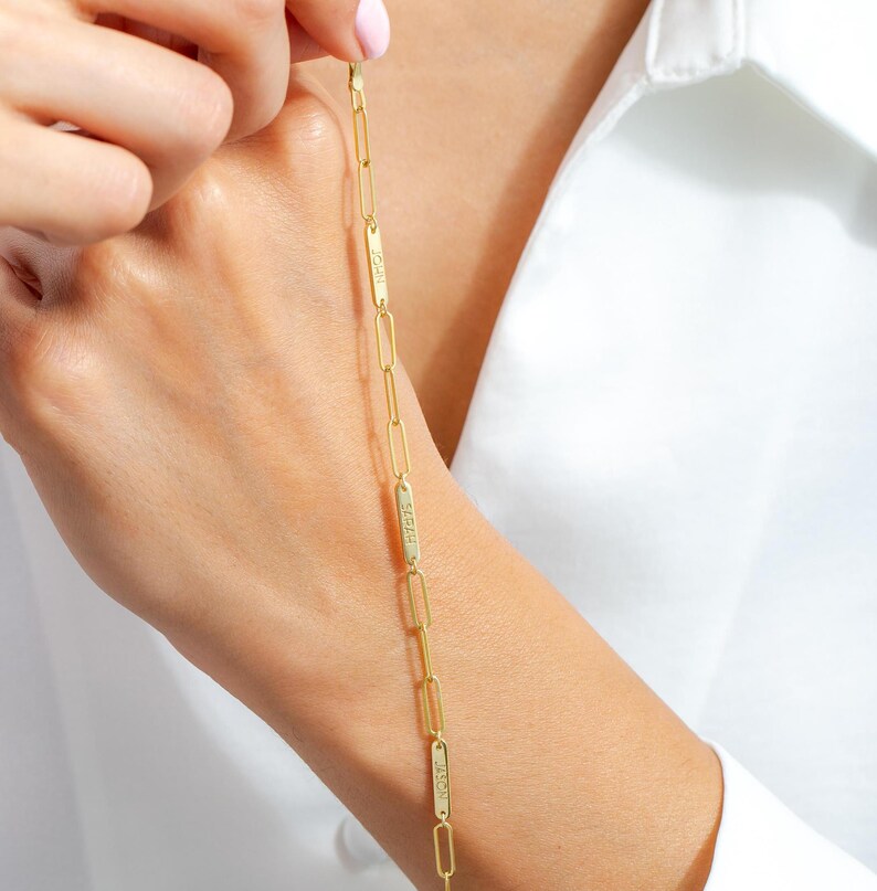 May include: A gold chain bracelet with rectangular links that have the word "LOVE" engraved on them.