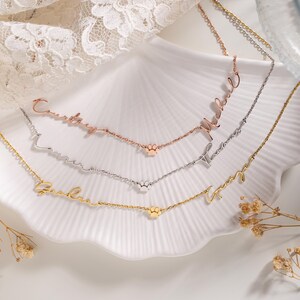 May include: Three gold, silver, and rose gold necklaces with paw print charms. Each necklace has a personalized name in cursive script. The names are "Courtney", "Lauren", "Gabriel", "Maxwell", "Thomas", and "Amy".