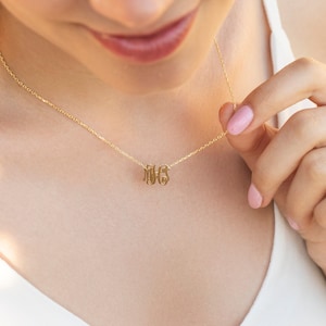 May include: A gold chain necklace with a delicate monogram pendant featuring the letters "MHS".