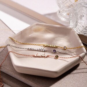 May include: Three delicate gold, silver, and rose gold necklaces with personalized names "grace", "camille", and "kathy" and a small gemstone accent on each.