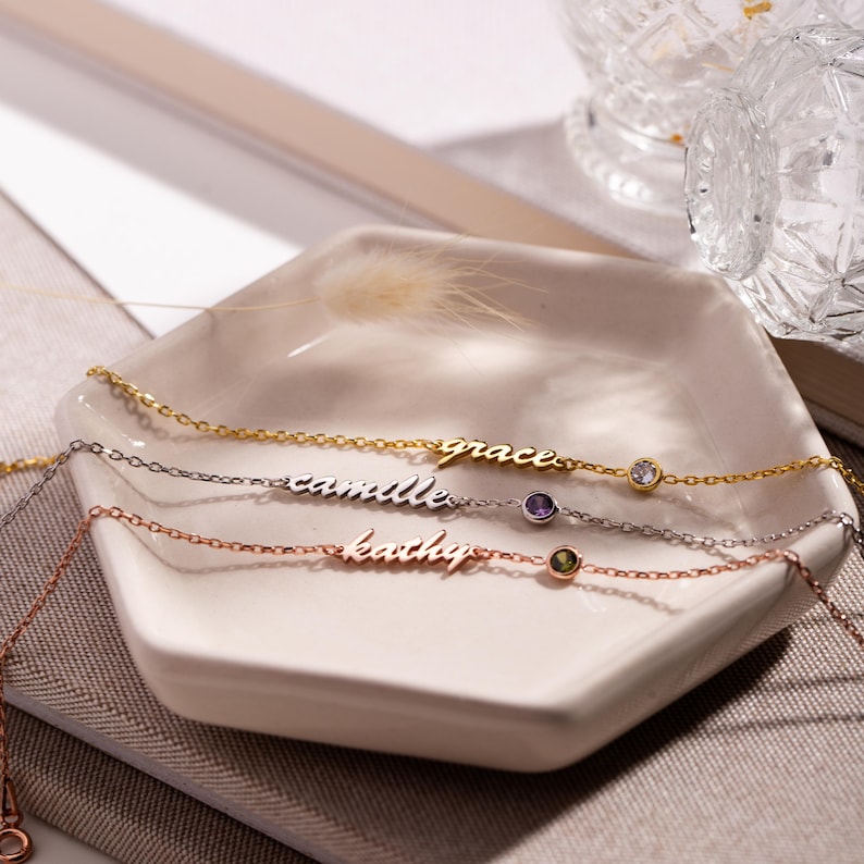 May include: Three delicate gold, silver, and rose gold necklaces with personalized names "grace", "camille", and "kathy" and a small gemstone accent on each.