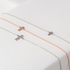 Pu&ograve; includere: Quattro delicate collane con croci in argento e oro rosa. Ogni collana presenta un piccolo ciondolo a forma di croce attaccato a una sottile catena. Le collane sono esposte su una superficie bianca, mettendo in risalto il loro design minimalista e l'elegante semplicit&agrave;.