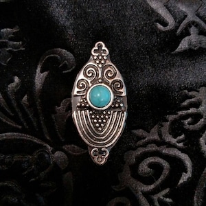 May include: A silver ring with a turquoise stone set in a decorative design. The ring is on a black background.