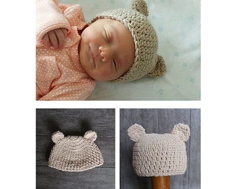 May include: A beige crocheted baby hat with bear ears. The hat is shown on a wooden surface and on a baby.