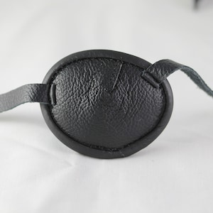 May include: A black leather eye patch with a strap.