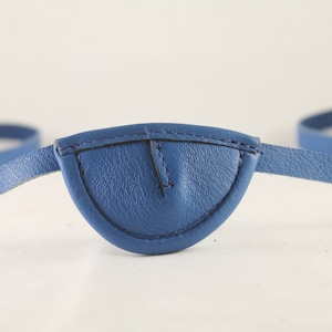 Puede incluir: Un parche para el ojo de cuero azul con una correa ajustable.