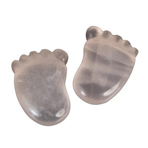 Può includere: Due sculture a forma di piede in quarzo rosa. Le sculture sono di colore rosa pallido e traslucido. Le dita dei piedi e i talloni sono ben definiti. Ogni scultura misura circa 5 cm di lunghezza ed è lucidata.