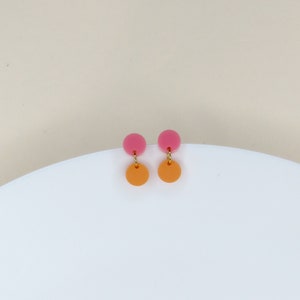 Könnte beinhalten: Ein Paar rosa und orangefarbene Ohrringe. Die Ohrringe sind aus Acryl und haben ein schlichtes, modernes Design.