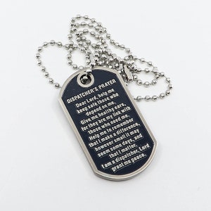 May include: A black metal dog tag necklace with a silver chain. The dog tag has the words "Dispatcher's Prayer" engraved on it, along with a prayer for safety and peace.