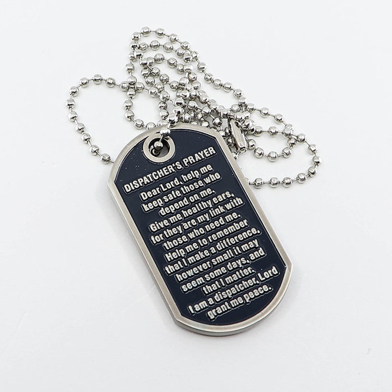 May include: A black metal dog tag necklace with a silver chain. The dog tag has the words "Dispatcher's Prayer" engraved on it, along with a prayer for safety and peace.