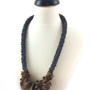 May include: A gray and brown fabric necklace with a large, ruffled brown fabric flower pendant.