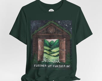 May include: Dark green t-shirt featuring a watercolor painting of a wooden structure with open doors revealing a green landscape. The text "FURTHER UP! FURTHER IN!" is printed below the image. The shirt has short sleeves.