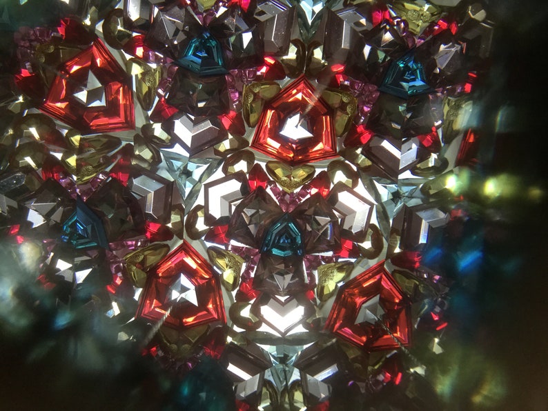 May include: A kaleidoscope image with a symmetrical pattern of red, blue, green, and gold geometric shapes.