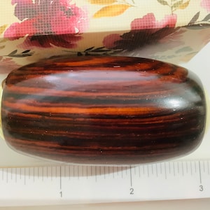 Puede incluir: Un pomo de madera marrón oscuro con detalles dorados. El pomo mide aproximadamente 5 cm de largo.