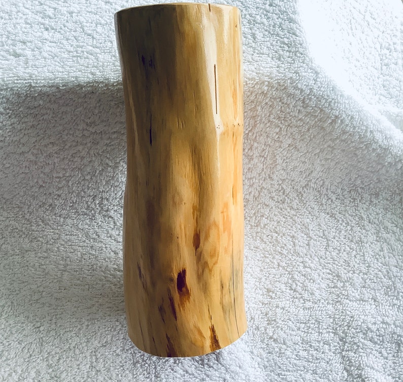 May include: A natural wood vase with a unique, irregular shape and a light brown colour. The vase has a smooth, polished finish and is perfect for displaying flowers or other decorative items.