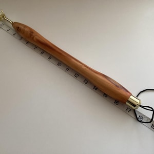 May include: A wooden back scratcher with a gold metal hand at the top and a gold metal tip at the bottom. The scratcher is about 18 inches long and has a black elastic band attached to the bottom.